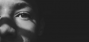 a closeup of a person in lit up, surrounded by shadow